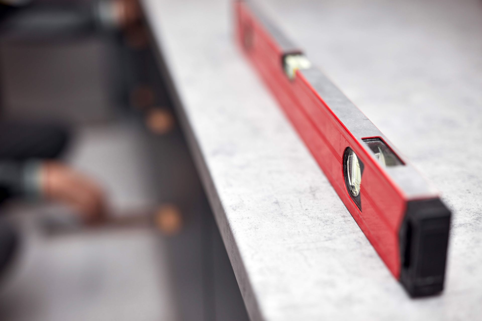 Red spirit level on a gray workbench in a blurred construction setting