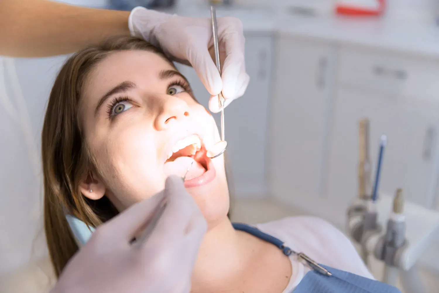 Dentist examining a patient with a mirror and dental tools in a bright clinic