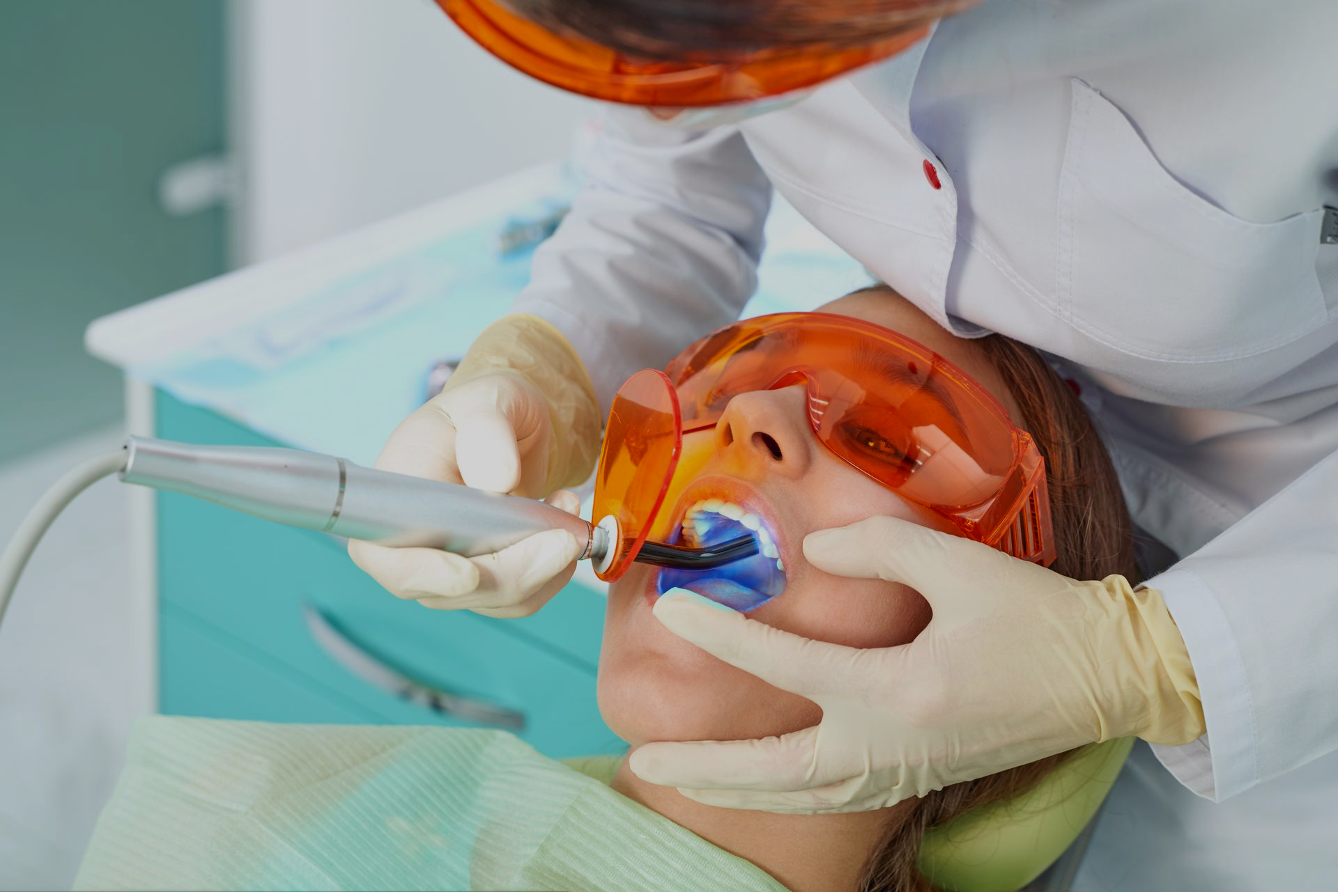 Dentist adjusting braces on a smiling patient’s teeth with pink gloves and tools