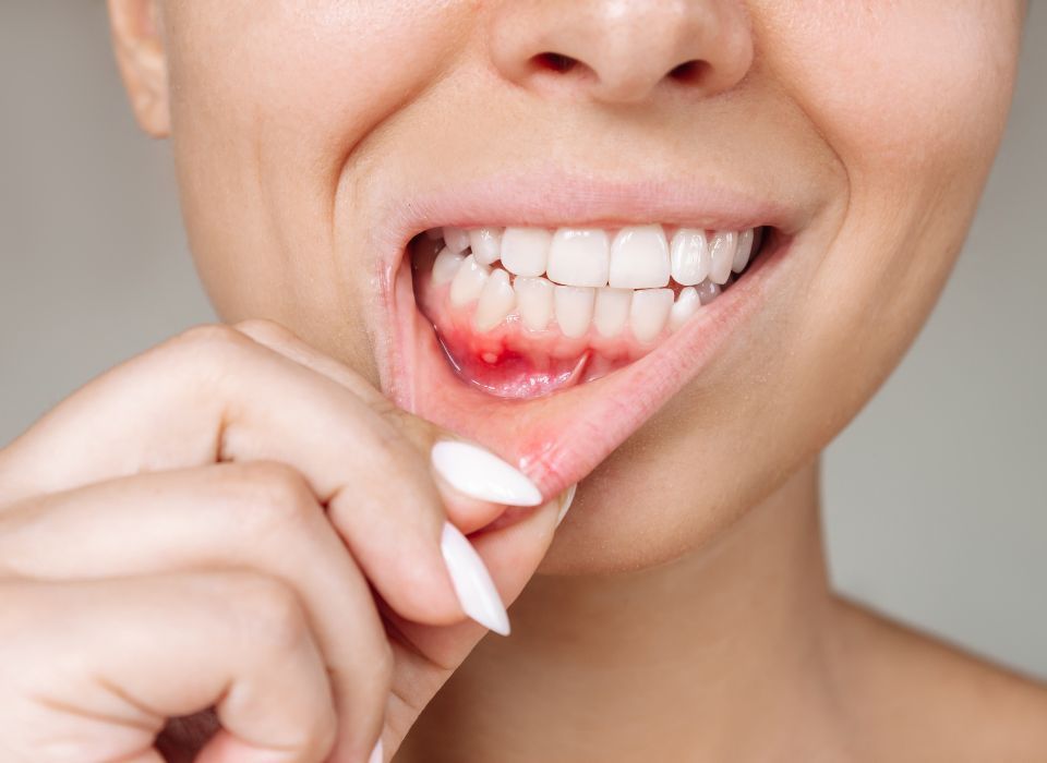 Person flossing teeth with a smile, showing gums and white teeth in close-up.