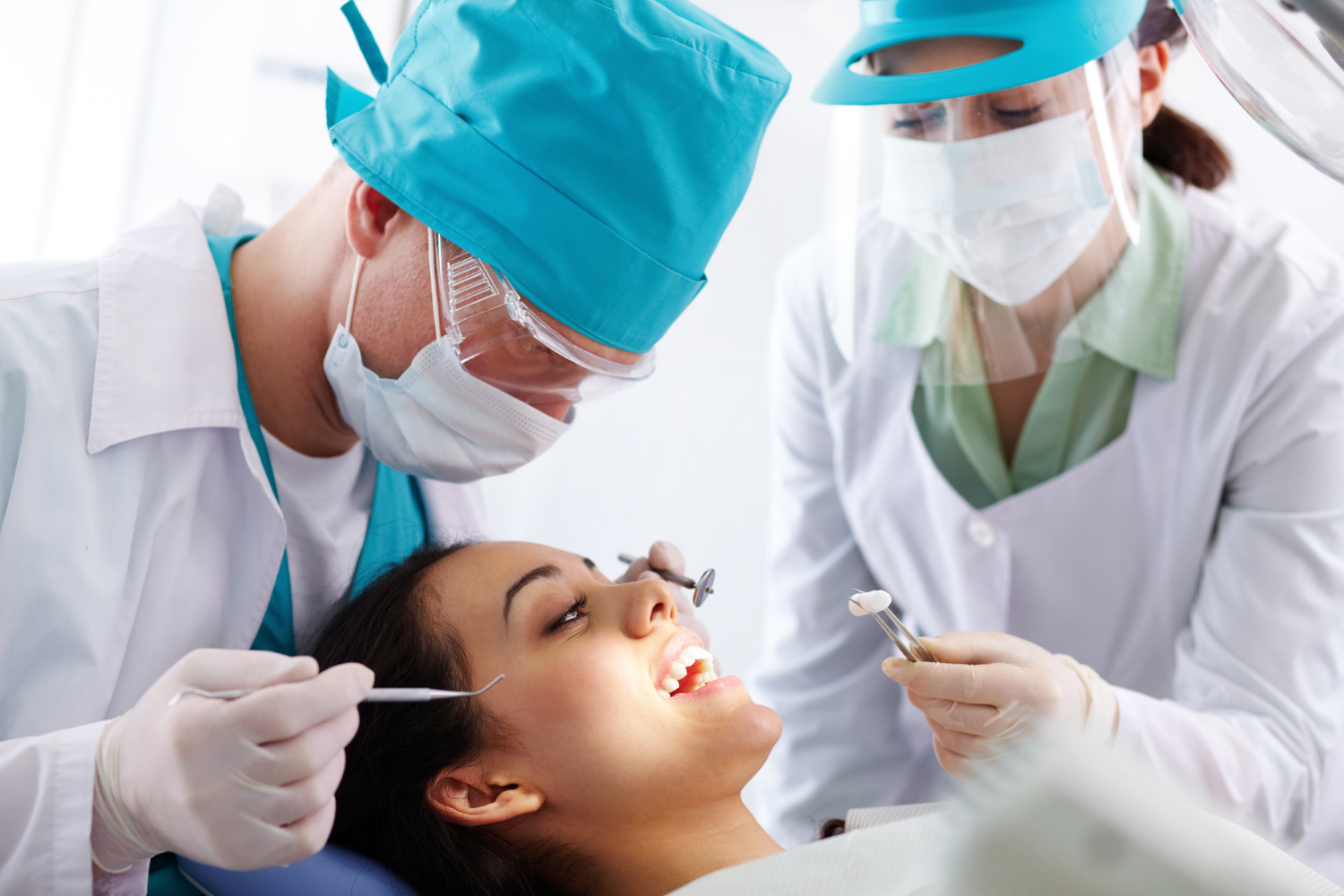 Dentist and assistant treat a reclining patient in a bright dental clinic