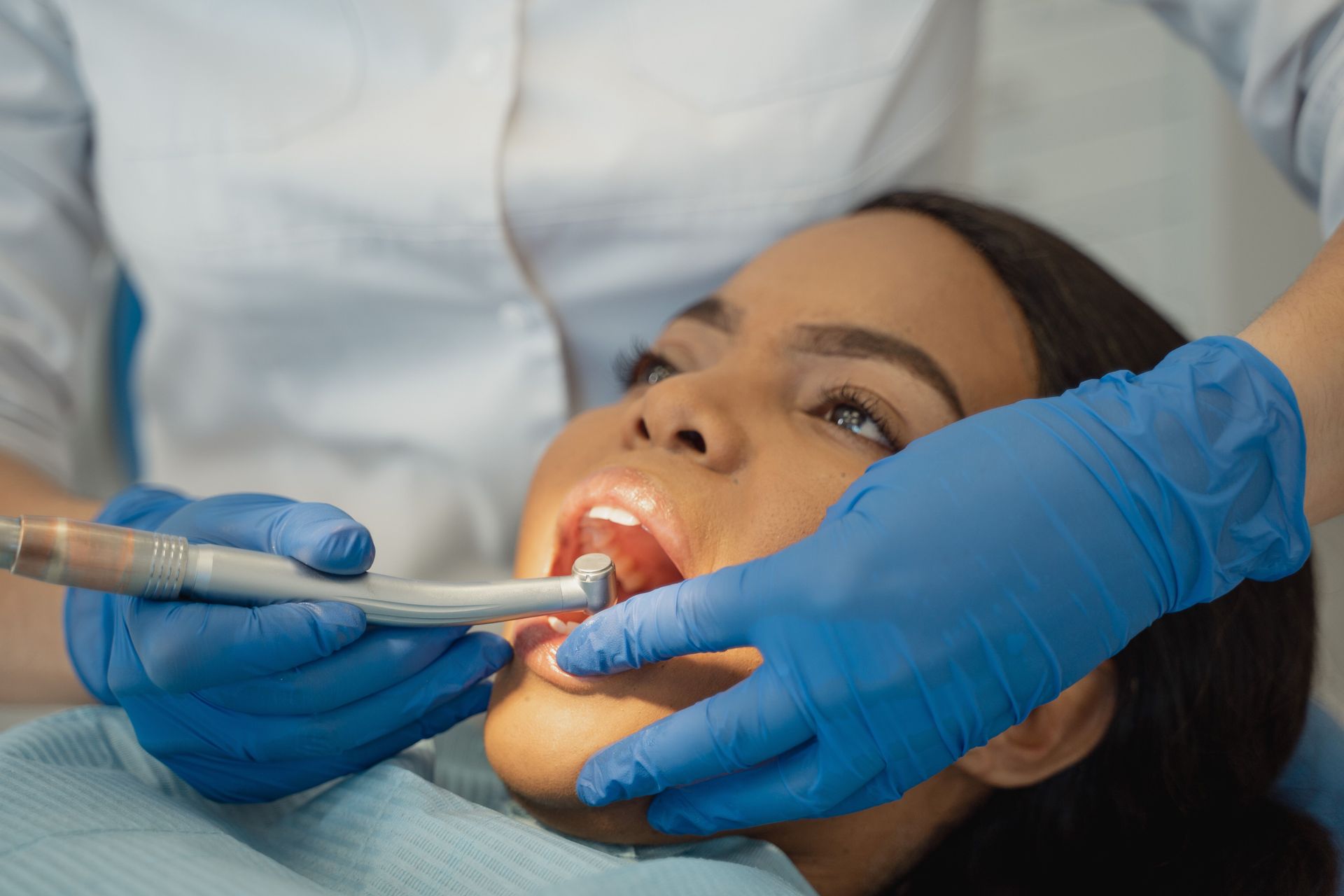 Dentist using a dental tool and mirror inside a patient's open mouth during an exam