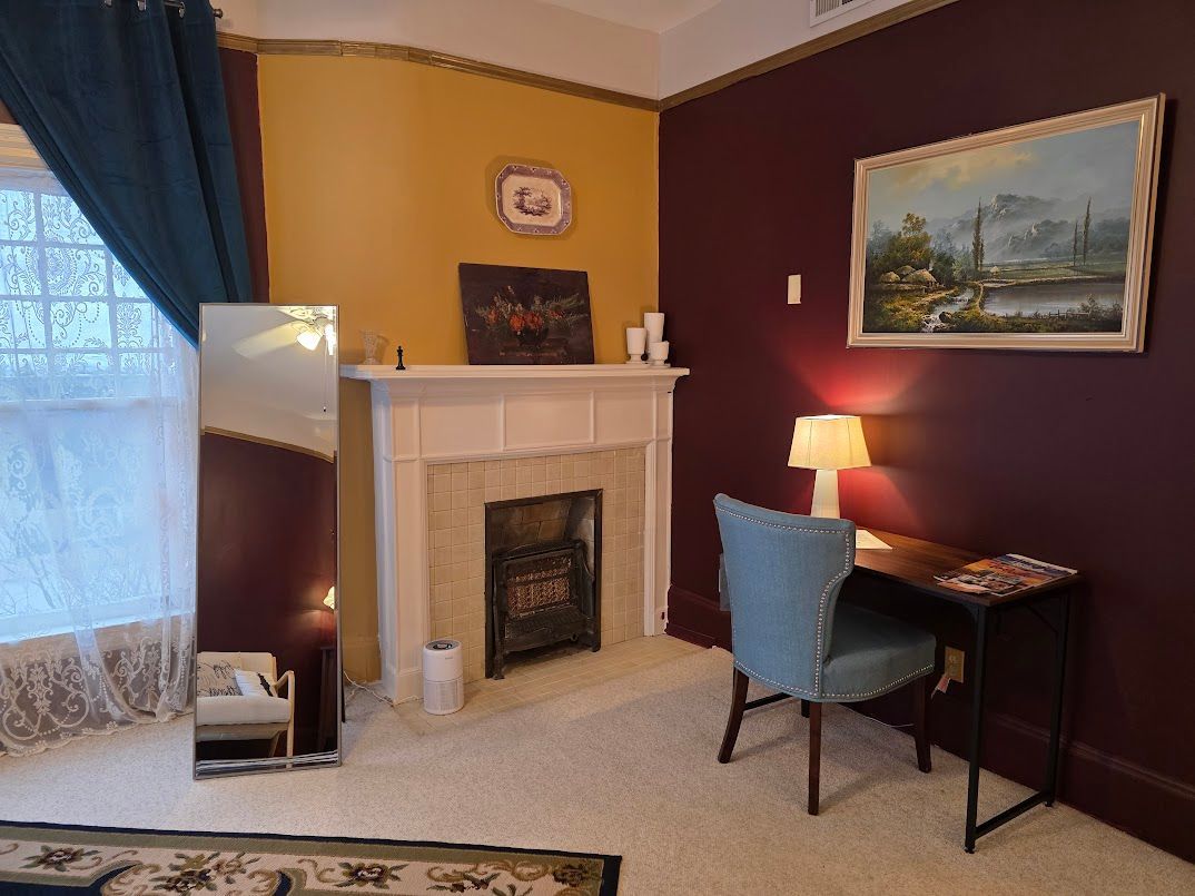 Room with maroon walls, fireplace, desk, mirror, and artwork; a cozy, interior setting.