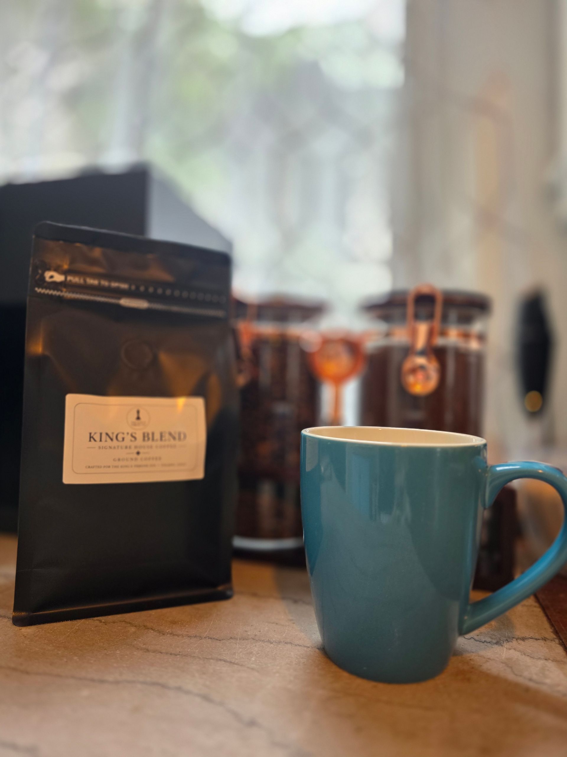Blue mug and coffee bag on a kitchen counter with a coffee maker in the background