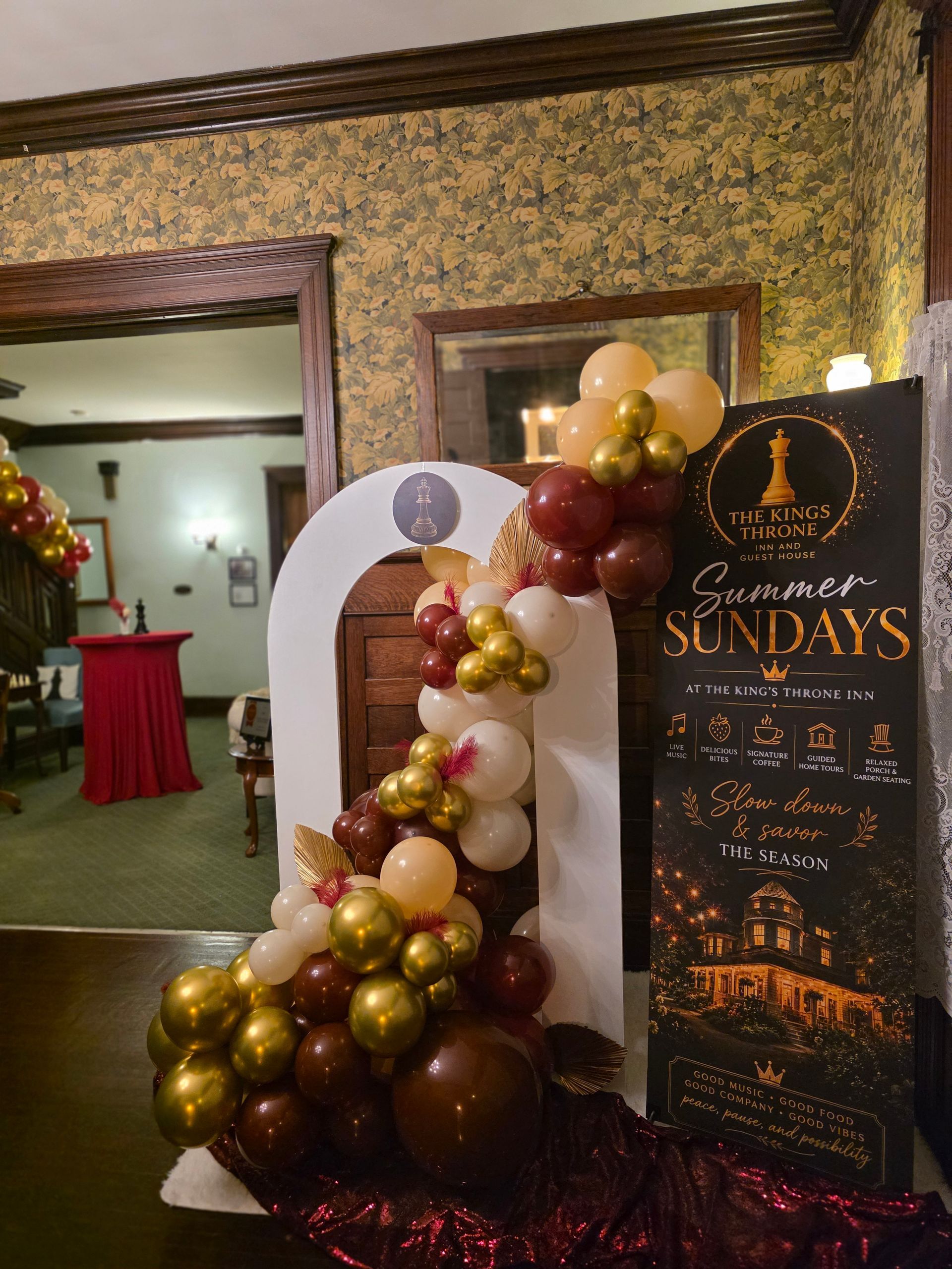 Decorated event entrance with balloon garland and a sign for “Sundays” in a vintage room