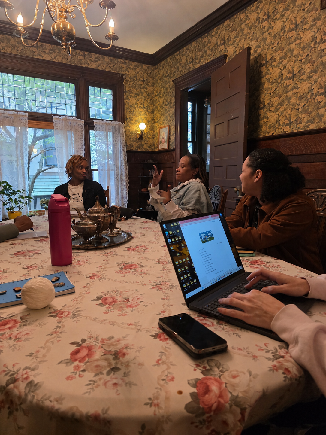 People seated around a dining table with laptops and drinks in a warmly lit room