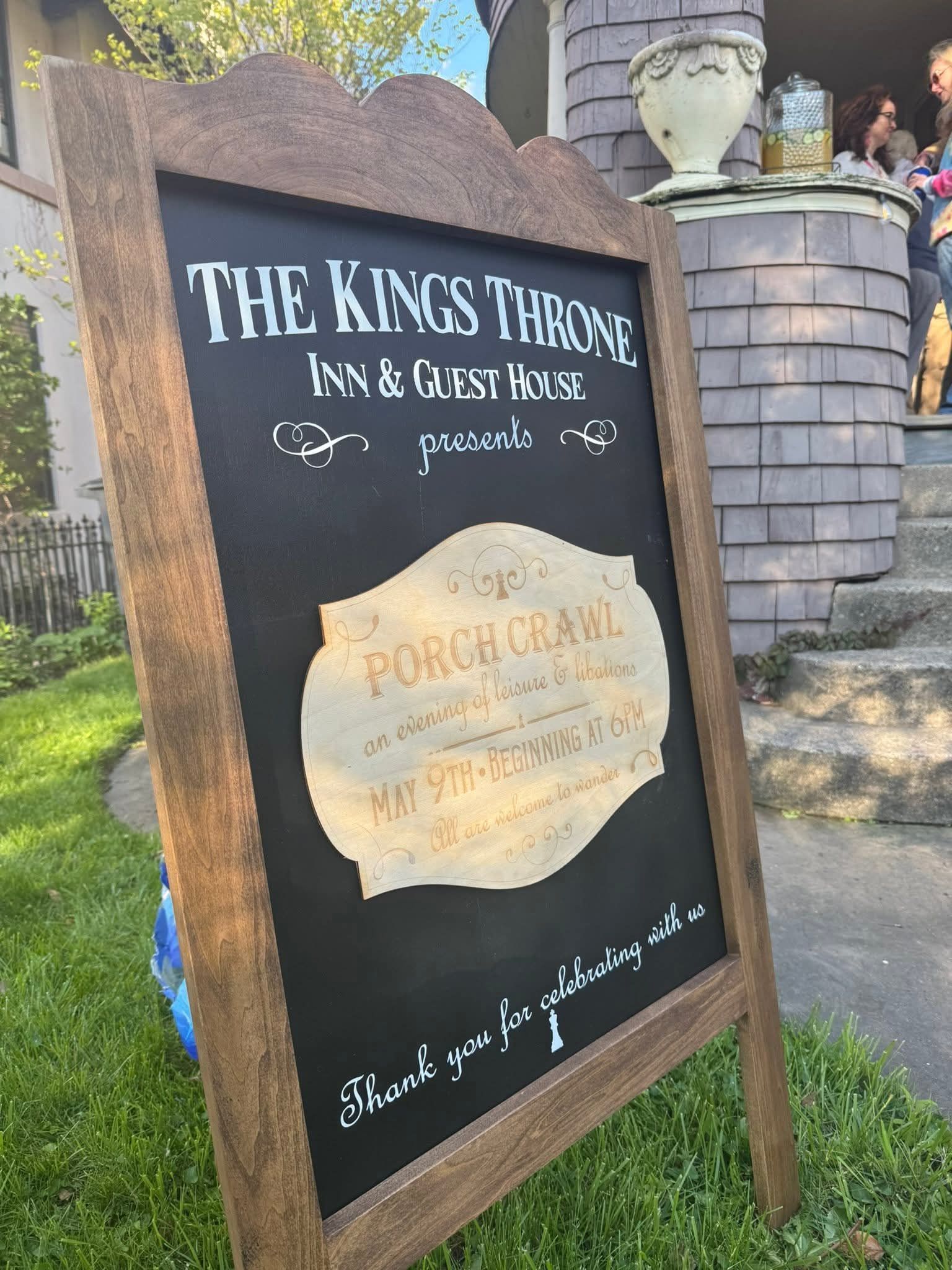 Wooden sign for “The King’s Tavern” with a chalkboard menu outside a stone building.