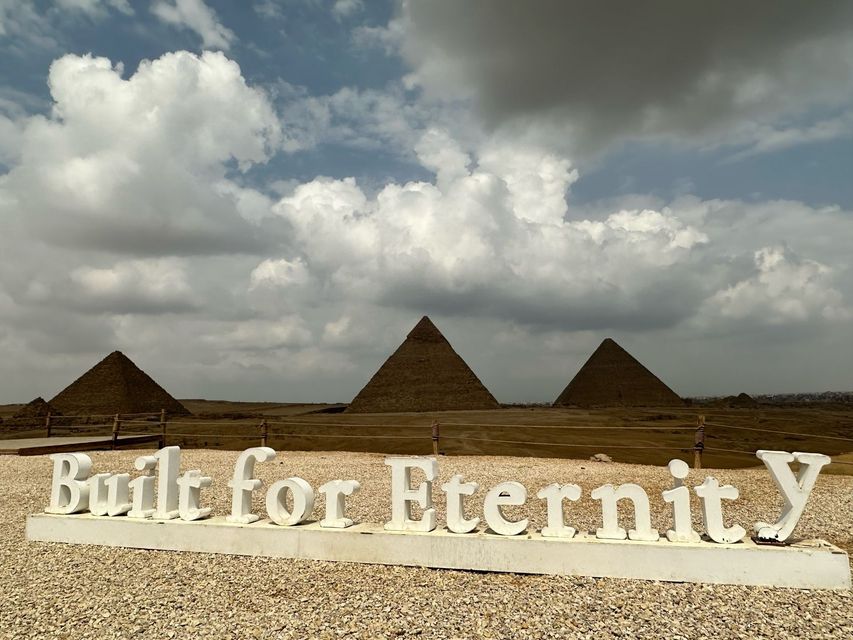Ancient Egyptian temple with colossal stone statues and columns in a sunlit desert courtyard