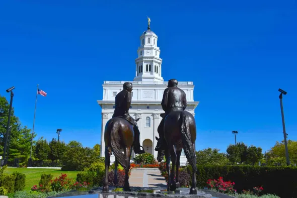 Equestrian statue before a white domed capitol building under a clear blue sky