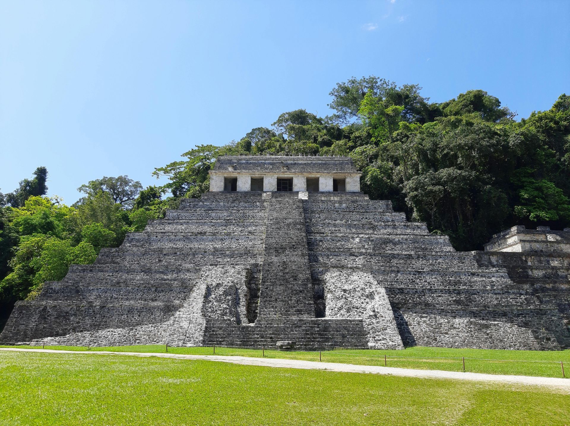 Ancient stone stepped pyramid amid lush green jungle under a clear blue sky