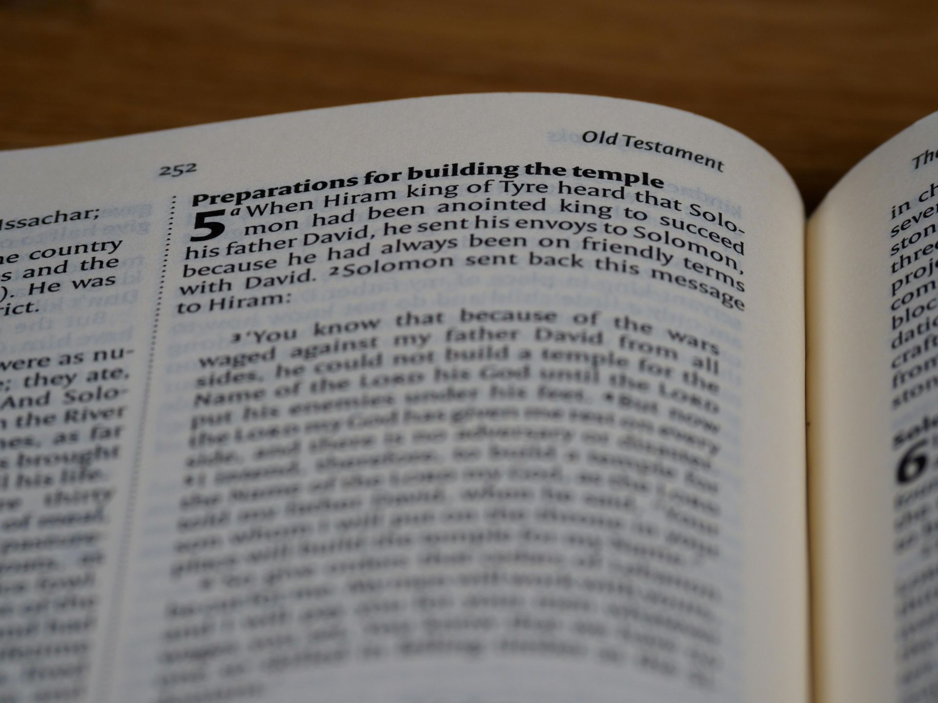Close-up of an open book page with dense text, slightly blurred and tilted on a desk.