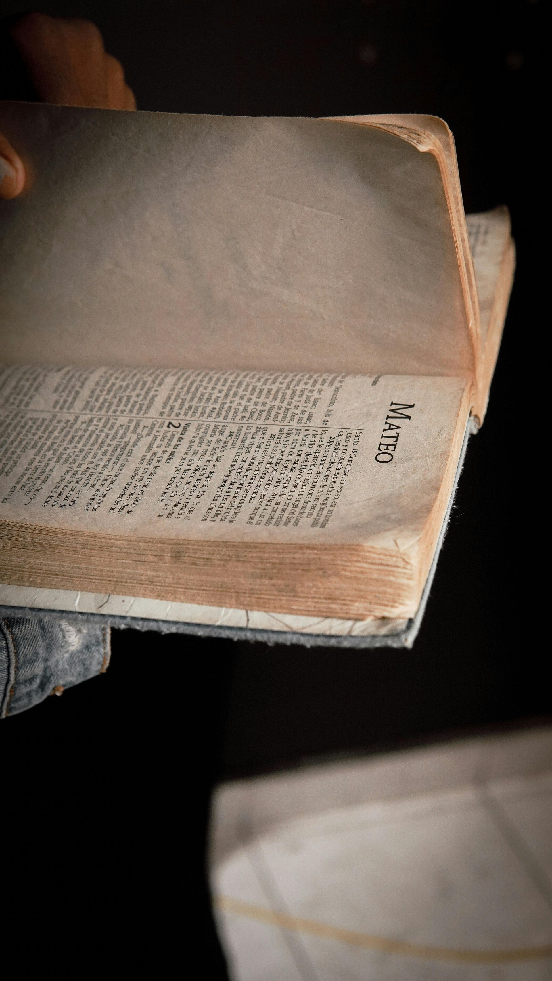Open book with handwritten notes, held by a person in dim light