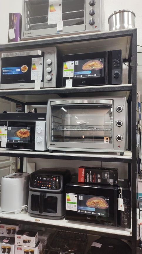 Estanterías con hornos de sobremesa y freidoras de aire expuestas en un pasillo de la tienda.