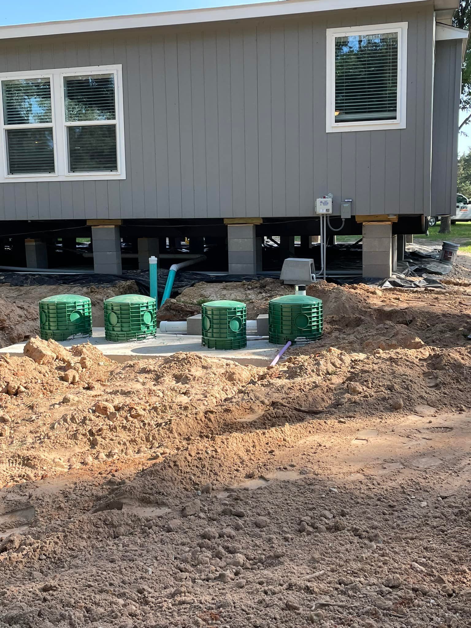 New house on raised foundation with dirt yard and green utility boxes in front