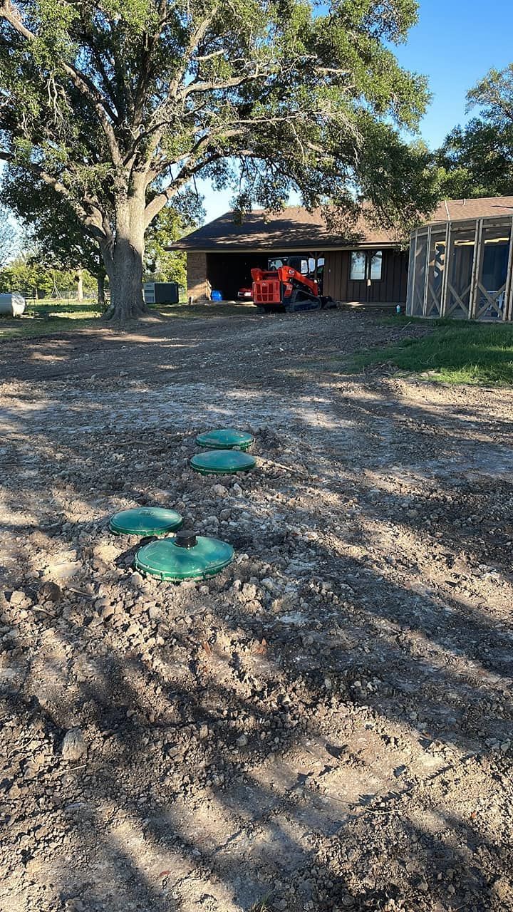 Large oak tree over a gravel yard, with a red tractor parked under a carport in the background.