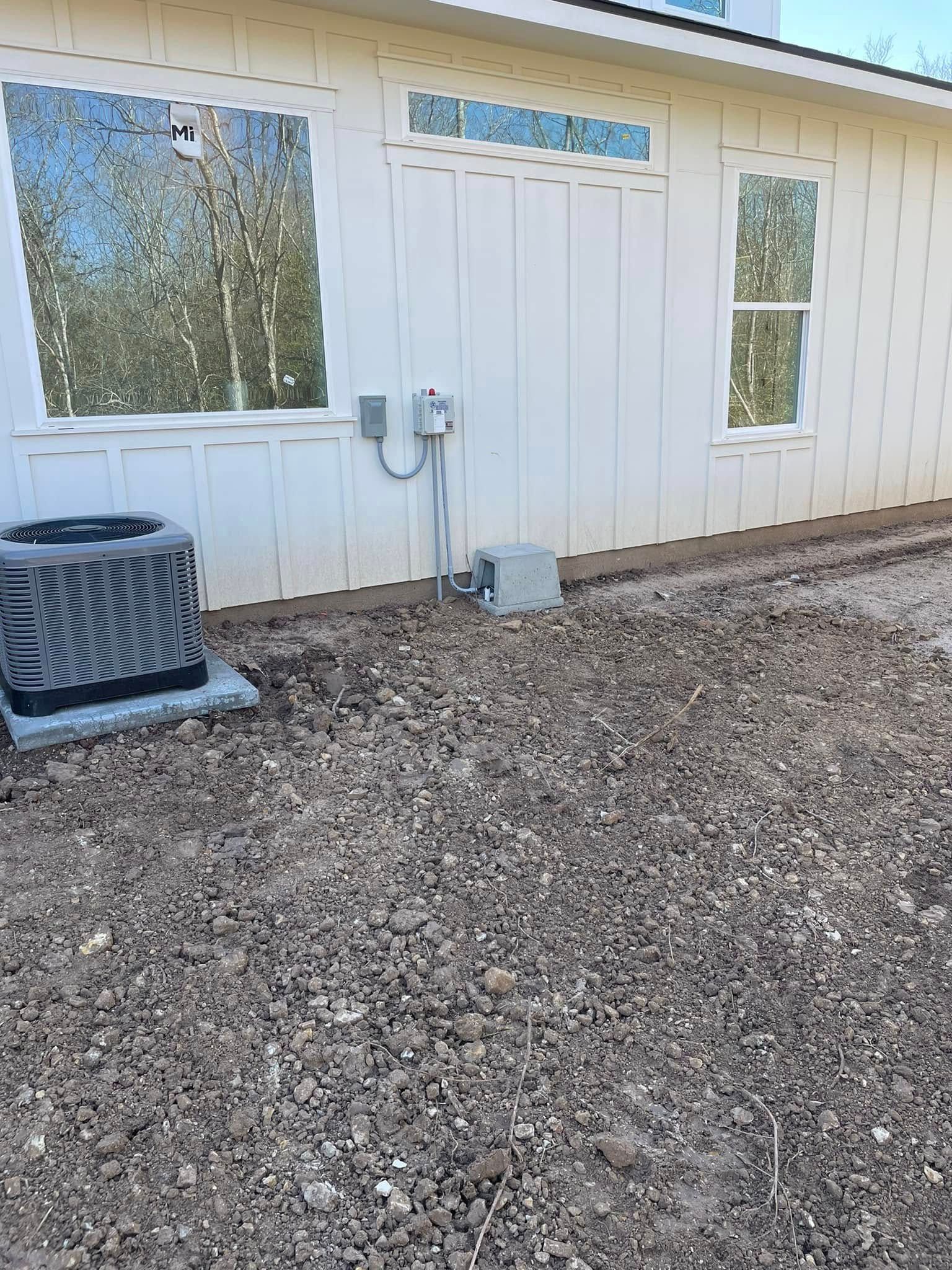 White building exterior with windows, utility meters, and a gravel ground area
