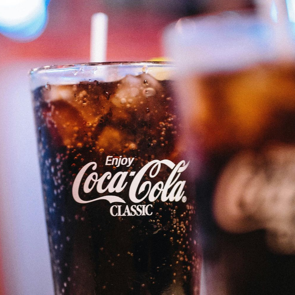 Two glasses of iced coffee with coffee ice cubes and milk being poured.