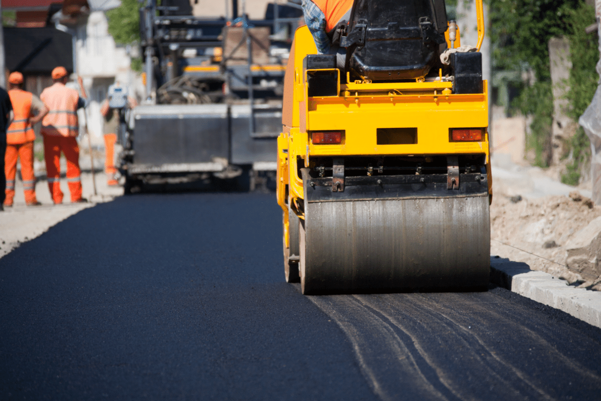 worker leveling fresh asphalt on a road construction