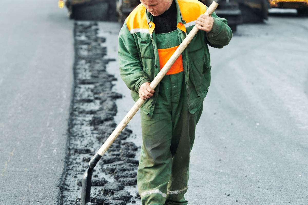 workers in reflective vests using shovels & drill during construction