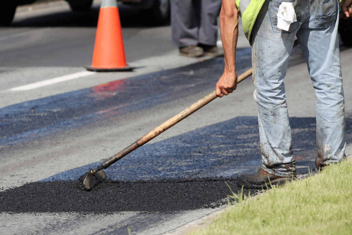 worker leveling fresh asphalt on a road construction