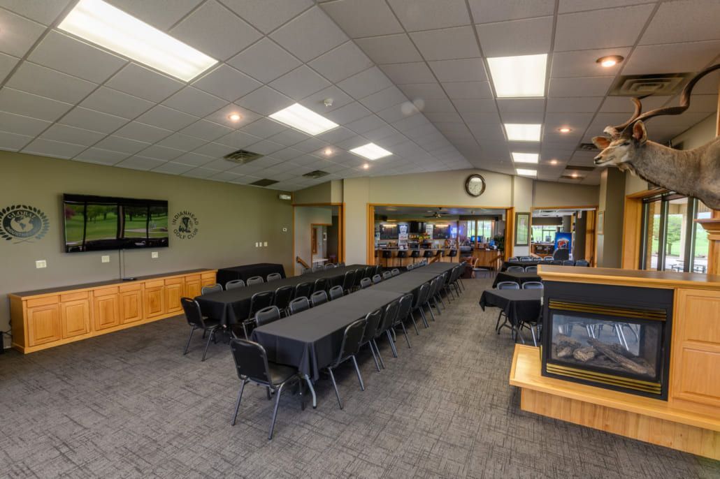 A large room with tables and chairs and a fireplace.