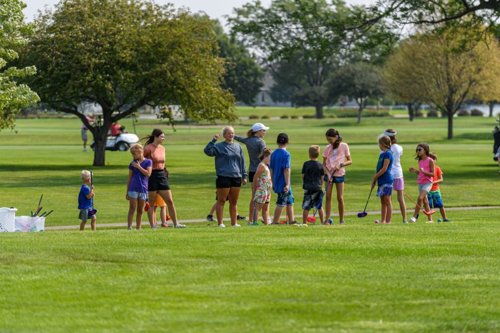 A group of people are standing on top of a lush green field.