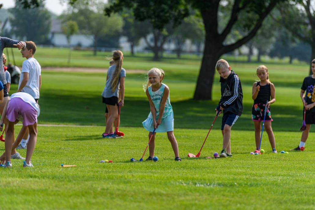 A group of children are playing golf on a golf course.