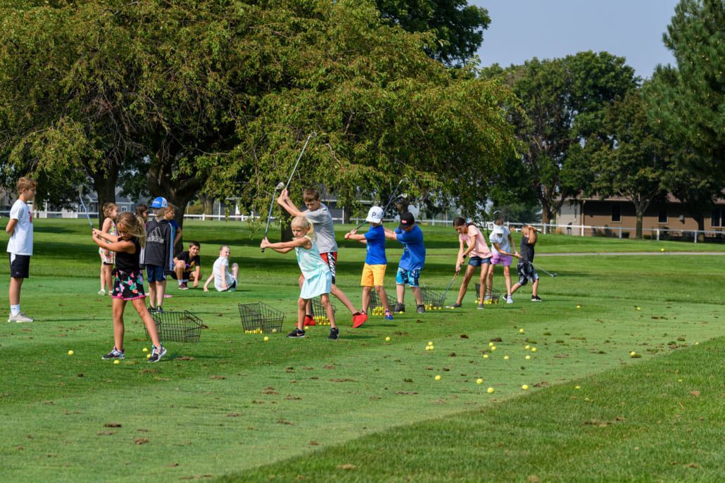 A group of children are playing golf in a park.