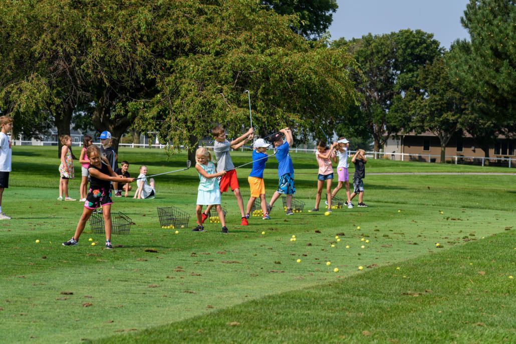 A group of children are playing golf on a golf course.