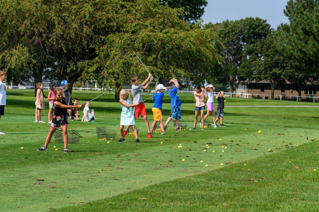 A group of children are playing golf on a golf course.