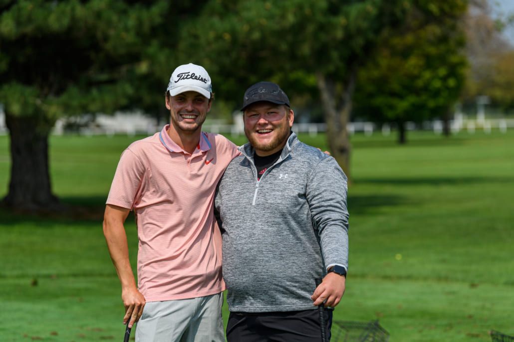 Two men are posing for a picture on a golf course.