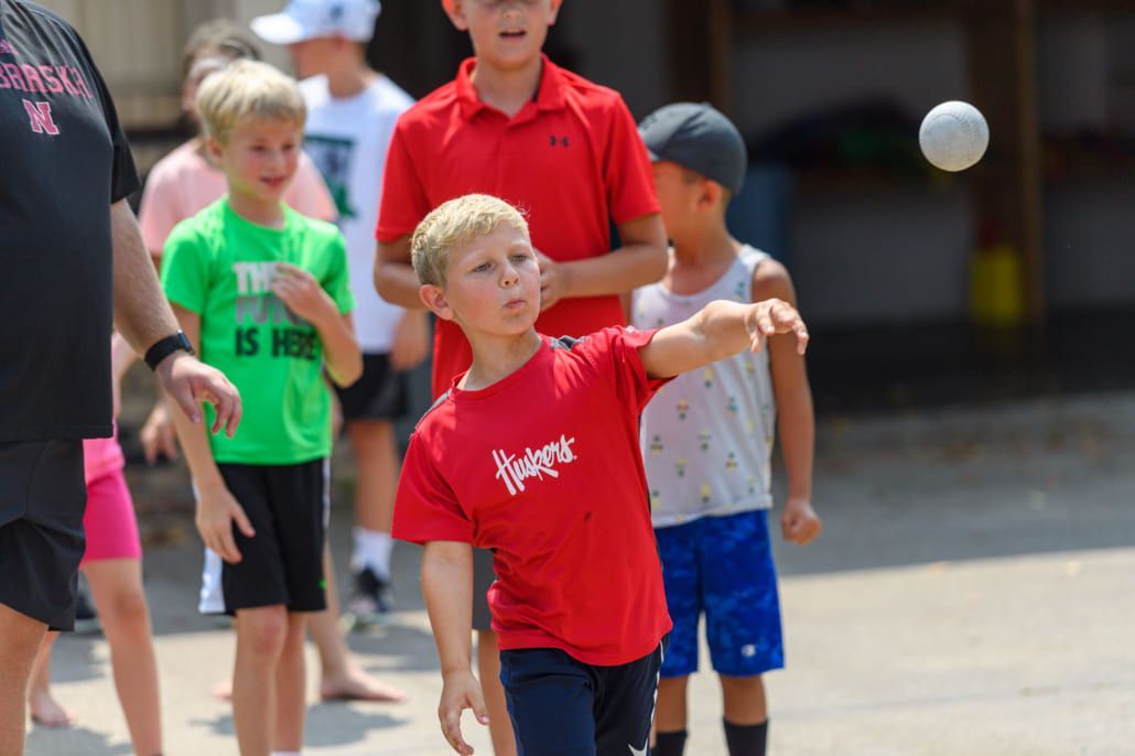 A young boy in a red shirt is throwing a ball.