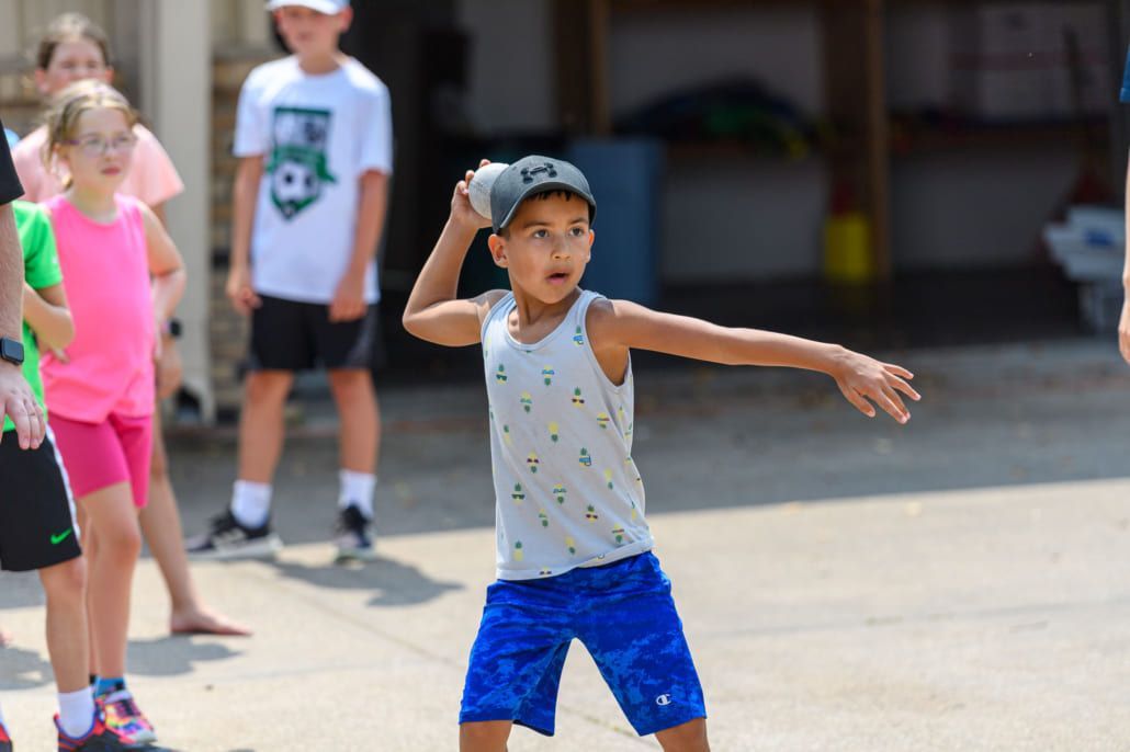 A young boy is throwing a ball in the air.