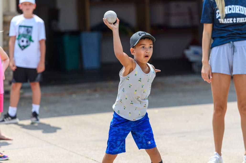 A young boy is throwing a baseball in the air.