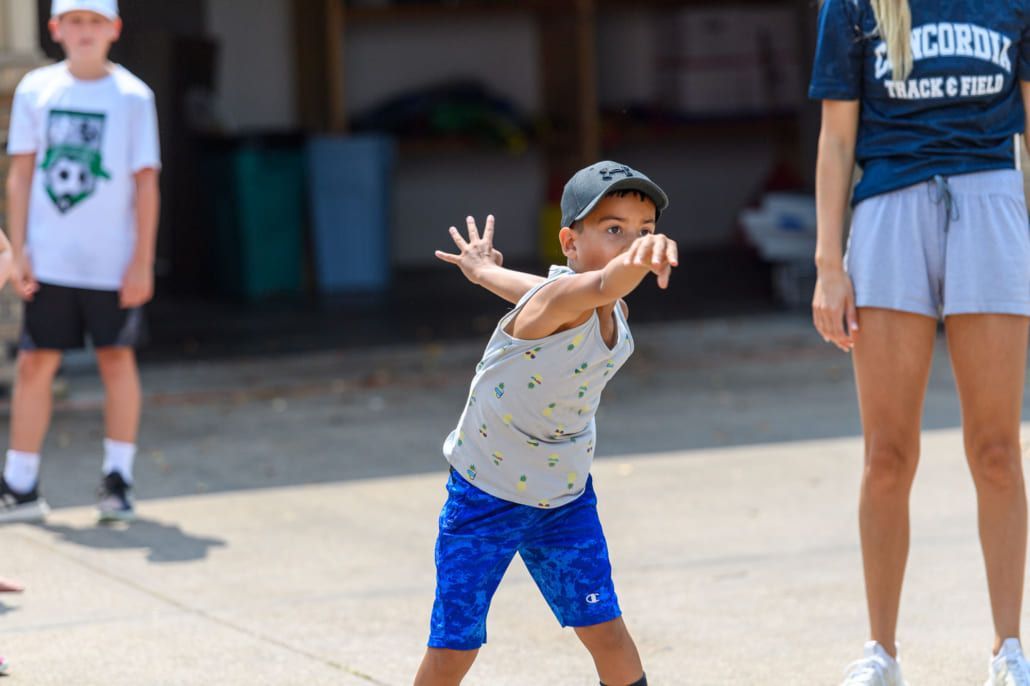 A young boy is standing on a skateboard in front of a group of children.