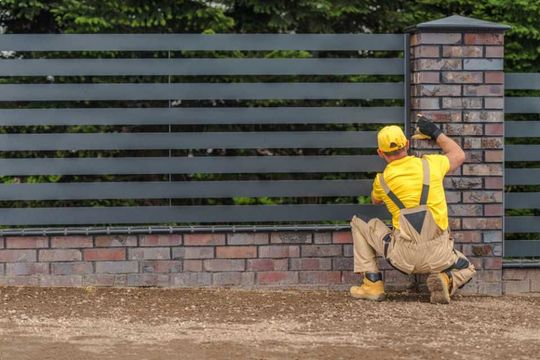 stylish metal panels fence building by professional fencing contractor worker