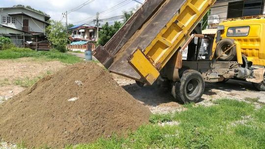 small dump trucks pour soil on the ground