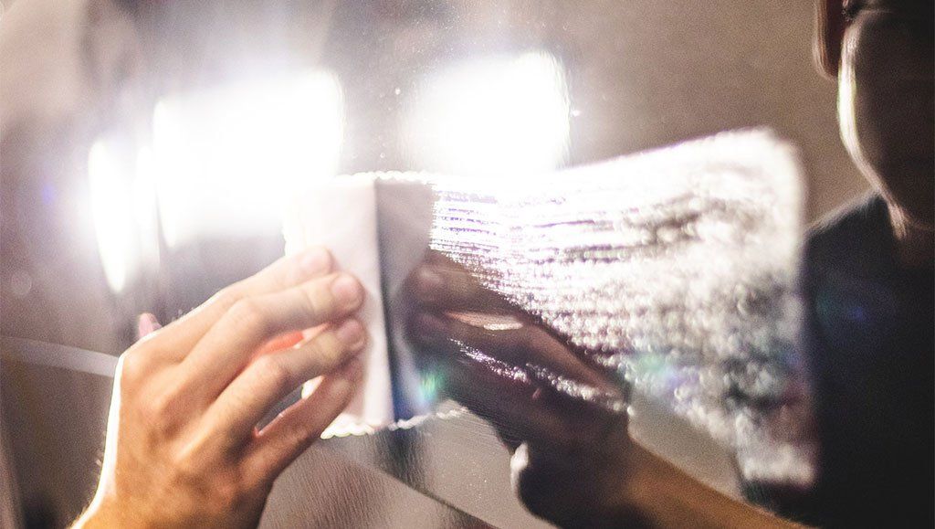 A person is holding a piece of paper in front of a mirror.