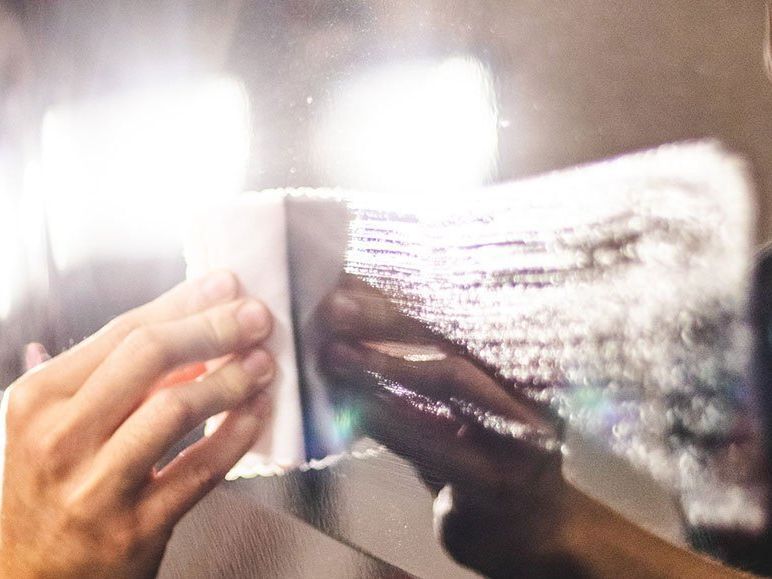 A person is cleaning a mirror with a sponge.