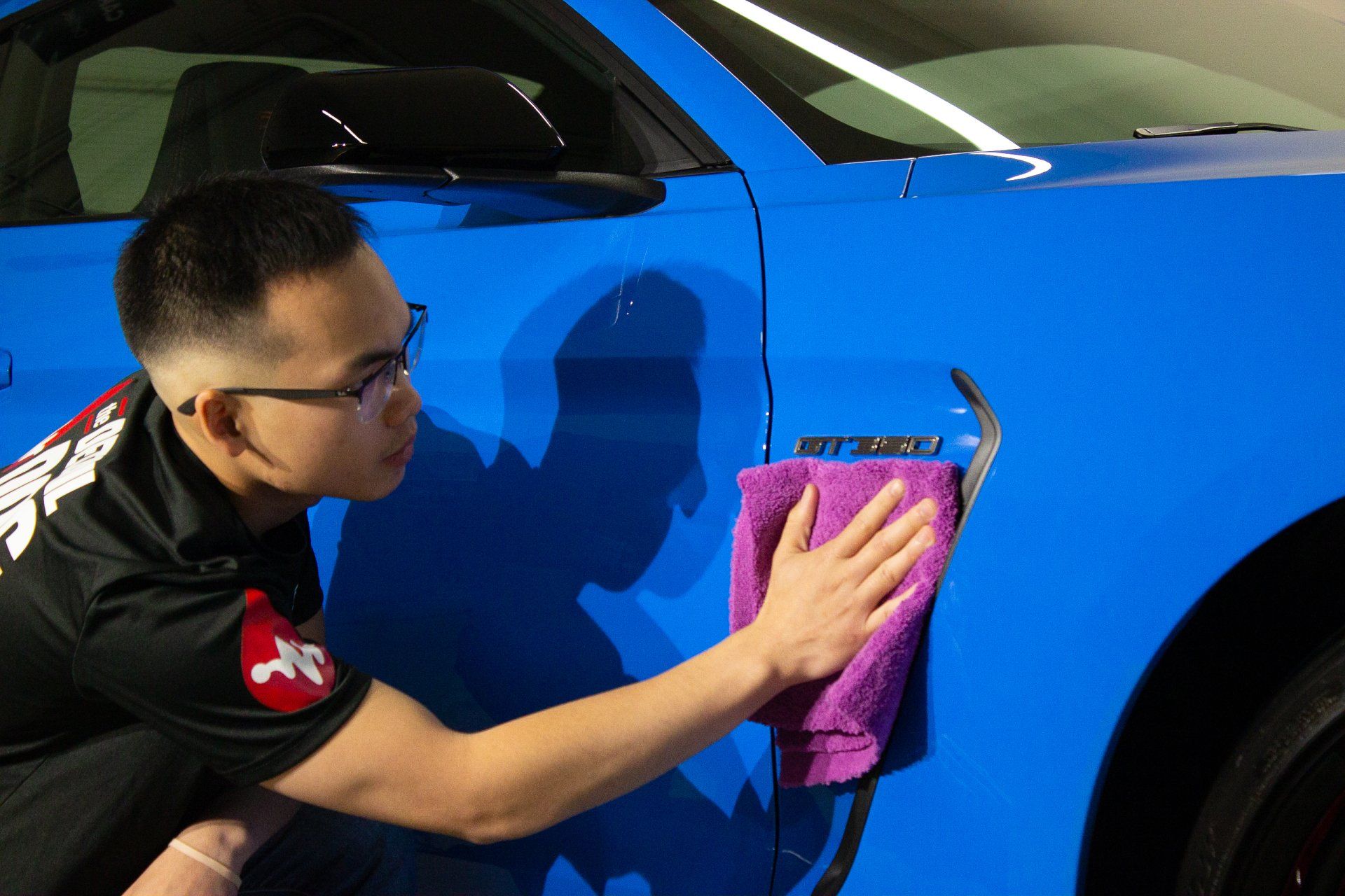 A man is applying a protective film to the side mirror of a car.