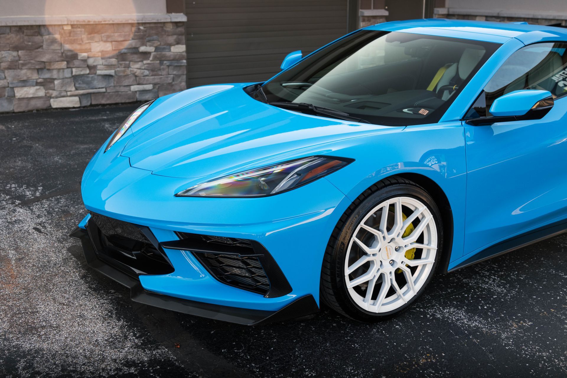 a blue sports car is parked in a driveway in front of a building .