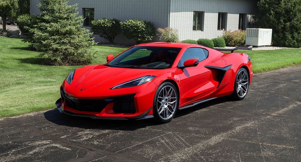 a red sports car is parked in a driveway in front of a building .