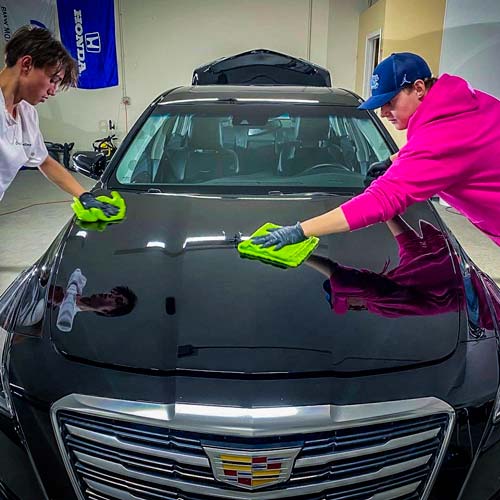 A man is applying a protective film to the headlights of a mercedes benz.