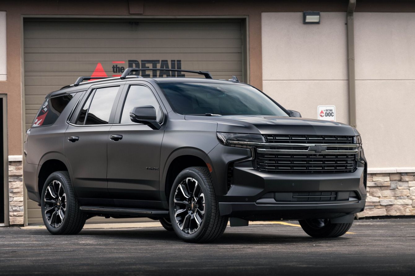 a black suv is parked in front of a garage door .