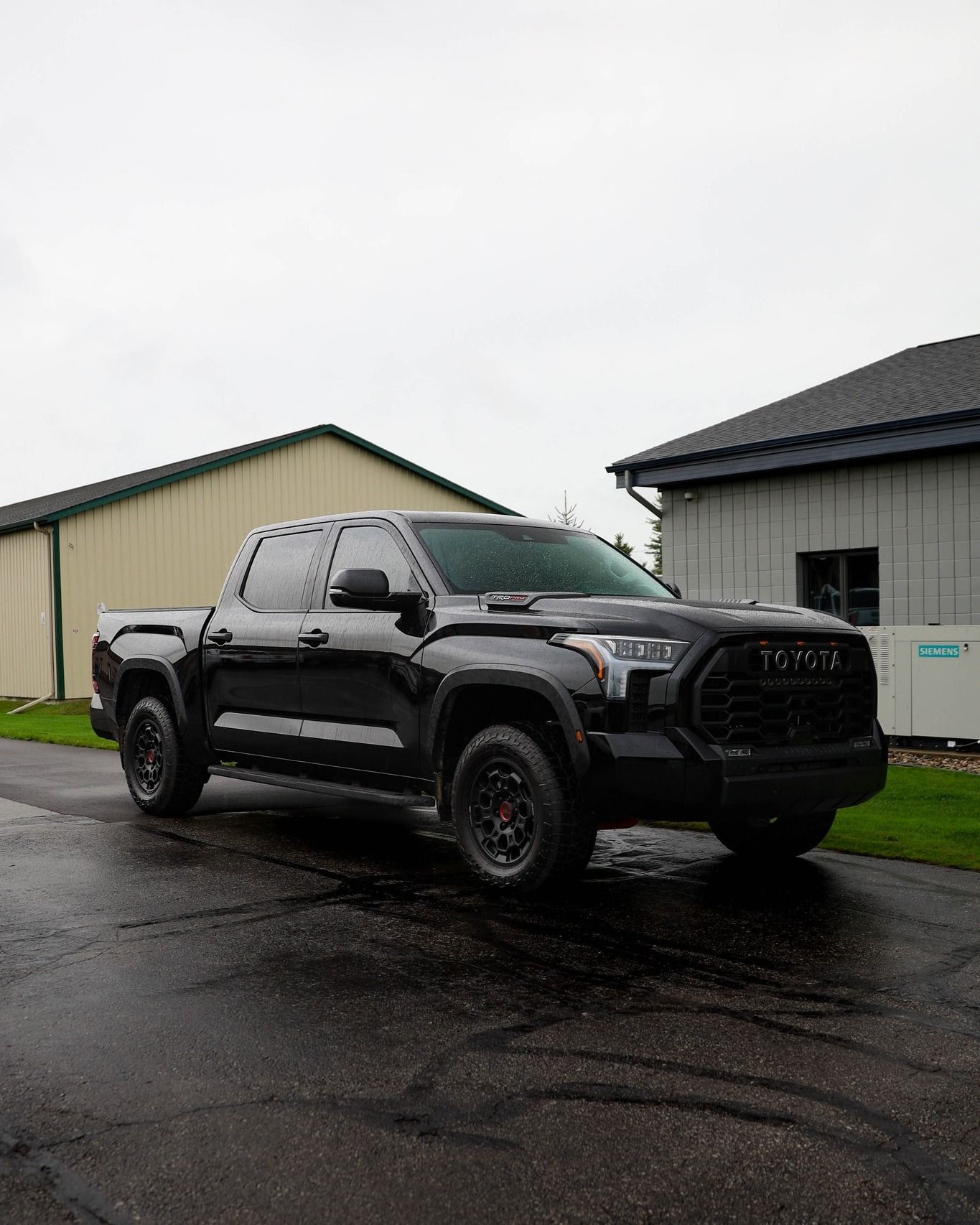 a black truck is parked on the side of the road in front of a building .