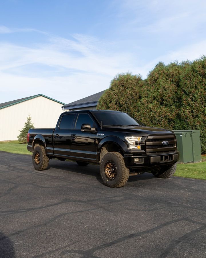 a black pickup truck is parked on the side of a road .