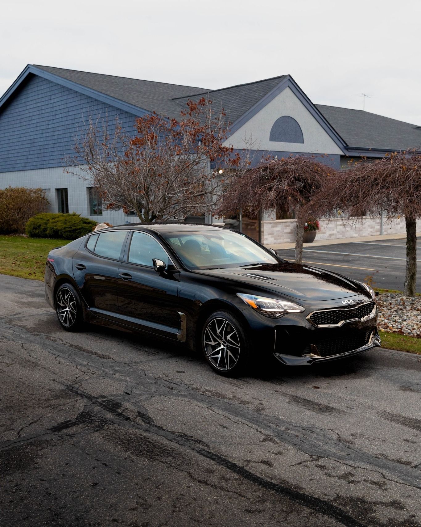 a black car is parked on the side of the road in front of a building .