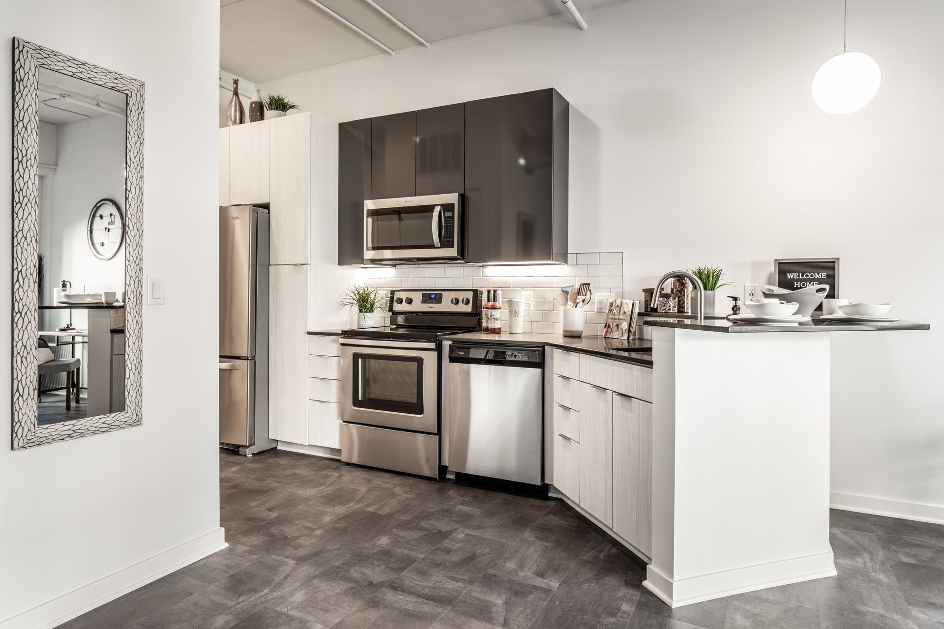 Modern kitchen with stainless steel appliances, white cabinets, and gray countertops.