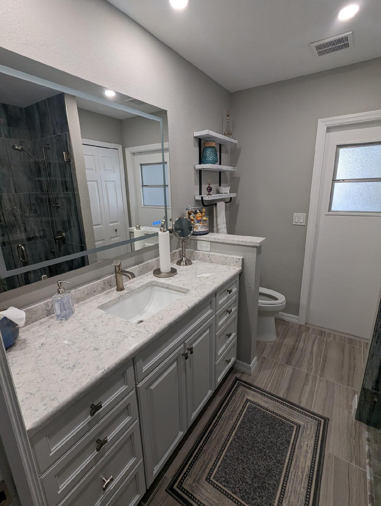 Bathroom with a long white vanity, white cabinets, and gray walls.