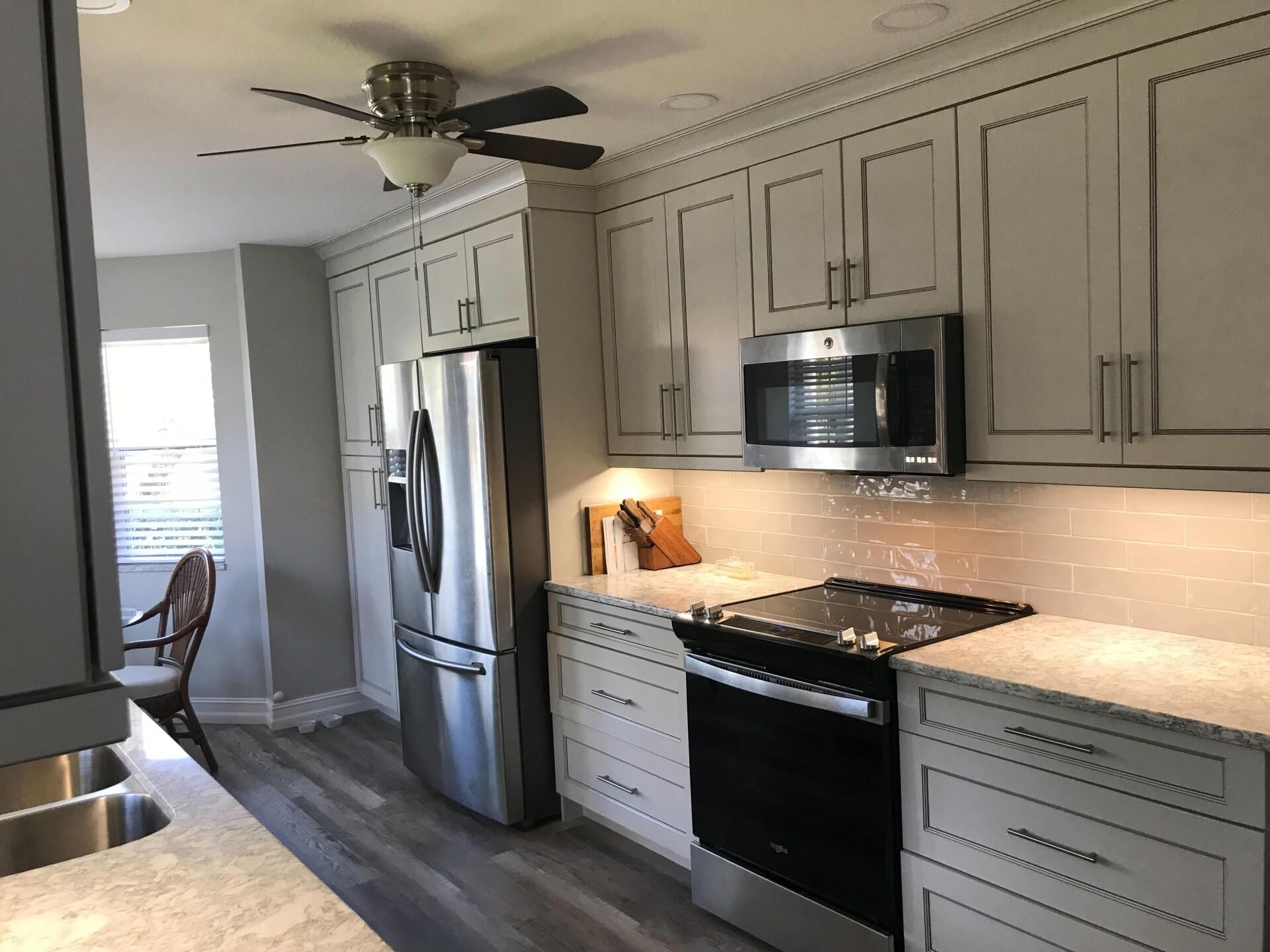 Kitchen with white cabinets, stainless steel appliances, and a dark stovetop.
